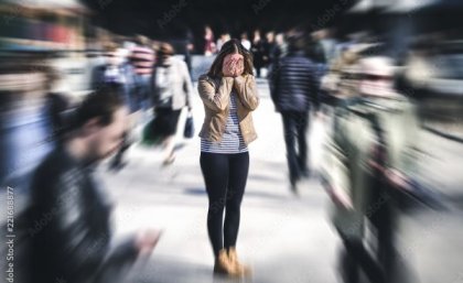 Woman standing with head in hands in middle of busy city. Adobe